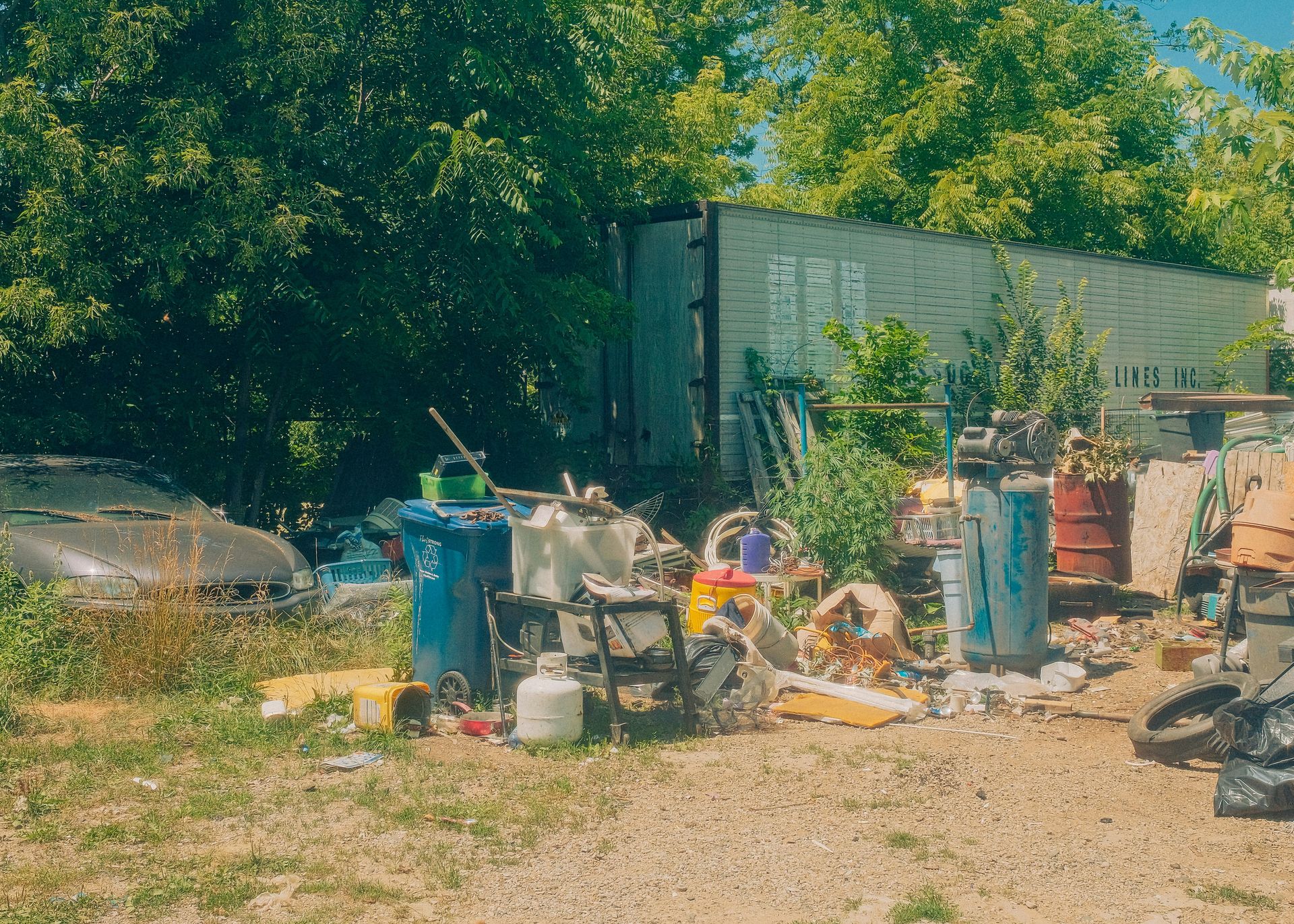 A cluttered yard with trash and a trailer house