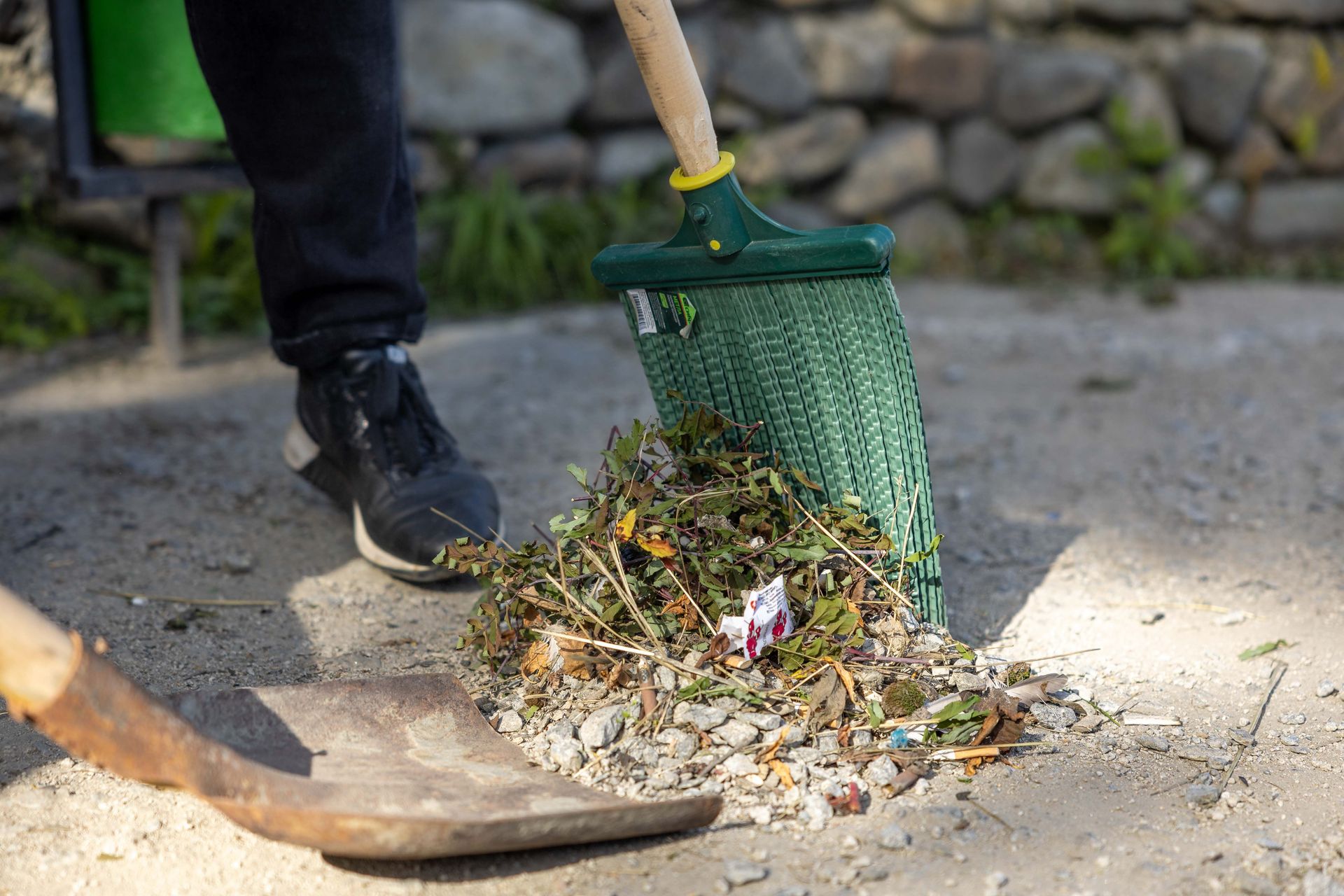 Close-up of a person raking leaves and debris outdoors.